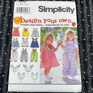 May include: Simplicity sewing pattern 9008 for a romper and dress. The pattern includes instructions for making a variety of styles, including a gingham dress and a striped romper. The pattern is for sizes AA 1/2, 1, 2.