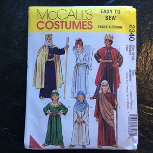 May include: A McCall's Costumes sewing pattern with illustrations of different costume designs. The pattern includes designs for characters such as a king, angel, and other historical or biblical figures. The package is labelled "Easy to Sew."