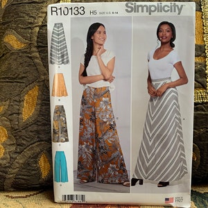 Peut inclure: Patron de couture Simplicity R10133 pour les tailles 6 à 14. Le patron comprend des instructions pour réaliser trois jupes différentes : une jupe rayée, une jupe fleurie et une jupe unie. Le patron est illustré avec des photos de mannequins portant les jupes.