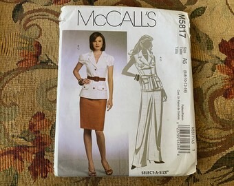 May include: A McCall's sewing pattern for a women's outfit, featuring a white blouse with a brown belt and a brown skirt, and a white vest with a brown belt and wide-legged pants. The pattern number is M5817 and the size is A5 (6-8-10-12-14).