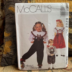 May include: McCall's sewing pattern for children's clothing, pattern number 6202 size 5, featuring a white blouse with a ruffled collar, black overalls, and a red and white patterned skirt.