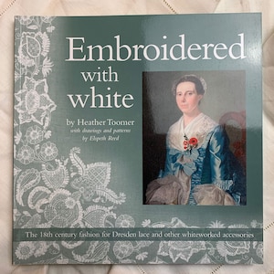 May include: Book cover with a teal background and white text that reads "Embroidered with white" by Heather Toomer with drawings and patterns by Elspeth Reed. The 18th century fashion for Dresden lace and other whiteworked accessories. The cover also features a white and gray floral design and a portrait of a woman in a blue dress.