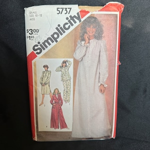 May include: Simplicity sewing pattern number 5737 for a nightgown, robe and pyjamas. The pattern is for sizes 10-12 miss. The pattern shows a woman wearing a white nightgown with a ruffled collar and cuffs. The pattern also shows a woman wearing a red robe with a belt and a woman wearing a floral print pyjama top and trousers.