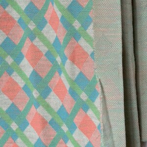 Puede incluir: Primer plano de una manta tejida con un patr&oacute;n de rombos rosa, azul y verde.