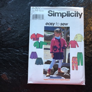 May include: Simplicity sewing pattern number 8307 for sizes 5, 6, 7, and 8. The pattern includes instructions for making a cardigan, a skirt, a long-sleeved shirt, and pants. The pattern is illustrated with a young girl wearing a pink cardigan and skirt.