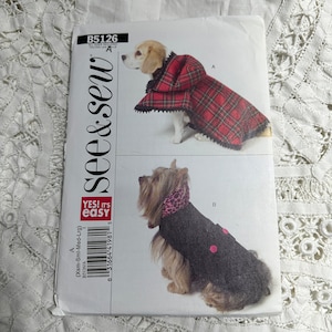 Può includere: Un cartamodello per due cappotti per cani. Il primo cappotto è una cappa con cappuccio a quadri rossi e neri. Il secondo cappotto è un cappotto nero con un cappuccio leopardato rosa e pois rosa. Il cartamodello è di see & sew ed è etichettato come B5126.