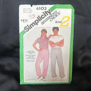 May include: Simplicity sewing pattern number 6103, level 2 beginner's choice, for stretch knits, includes two figures wearing pants and a shirt, the text 'Sized for stretch knits only' and 'See Pick-A-Knit rule on envelope back' is visible.