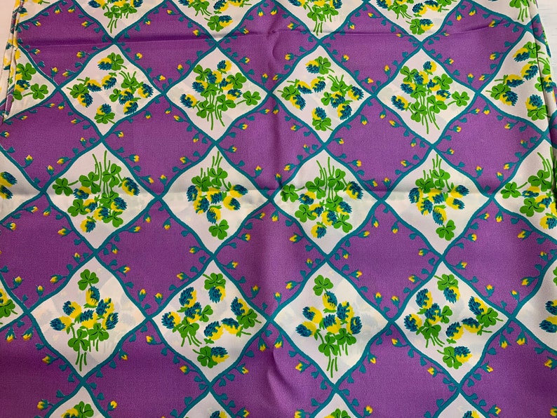 Pu&ograve; includere: Tessuto viola con un motivo a trifoglio bianco e verde. Il motivo a trifoglio si ripete a forma di rombo.