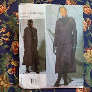 Pode incluir: Um padrão de costura para um casaco comprido roxo com gola alta e fecho de botões. O padrão é da Vogue Patterns e desenhado por Patricia Jeanne Keay. O número do padrão é V1529 e os tamanhos são 14-16-18-20-22.
