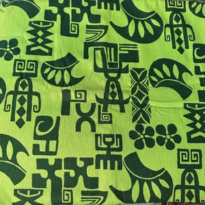 May include: Green fabric with a repeating pattern of black geometric shapes and stylized flowers. The pattern is reminiscent of Polynesian or Hawaiian art.