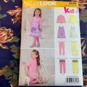 Può includere: Un cartamodello per abbigliamento per bambini, con una maglietta a maniche lunghe rosa e gialla, un vestito rosa e bianco e leggings rosa e gialli. Il cartamodello è di New Look ed è di taglia 4-7 anni, 92-4-110, Euro 112-4.