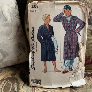 Può includere: Modello di cucito vintage Simplicity per una vestaglia, taglia 6. Il modello mostra due uomini che indossano vestaglie, una a quadri e una di colore blu tinta unita. Il numero del modello è 2338.