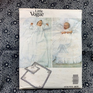 May include: A Little Vogue sewing pattern for a baby christening gown. The pattern includes a long gown with a ruffled hem and a matching bonnet. The pattern number is 2878.