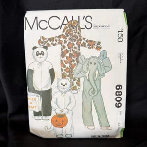 Könnte beinhalten: McCall's Schnittmuster mit Illustrationen von Tierkostümen: Panda, Katze, Elefant und Leoparden-Jumpsuit. Modellnummer 6809, Größe EX-SMALL. Enthält Text "McCall's".
