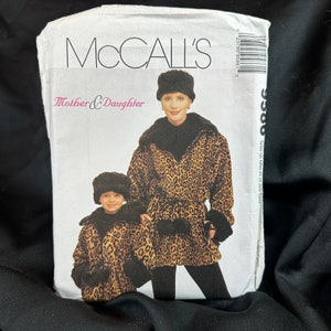 Pode incluir: Padrão de costura McCall's para um casaco de leopardo com guarnição de pele e chapéus combinando para mãe e filha. O número do padrão é 9388.