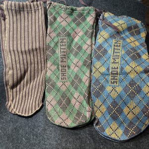 May include: Three knitted bags with different patterns. The first bag is brown and beige striped. The second bag is green, pink, and brown with a diamond pattern. The third bag is blue, yellow, and brown with a diamond pattern.