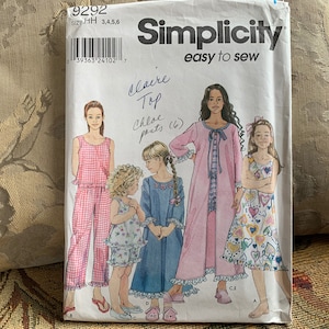 Può includere: Modello di cucito Simplicity 9292 per una blusa e pantaloni per bambina. Il modello include tre stili diversi: una blusa a quadri rosa e bianca con bordo a volant, una blusa a quadri blu e bianca con bordo a volant e una blusa a stampa floreale rosa e bianca con bordo a volant. Il modello include anche un paio di pantaloni a quadri rosa e bianchi.