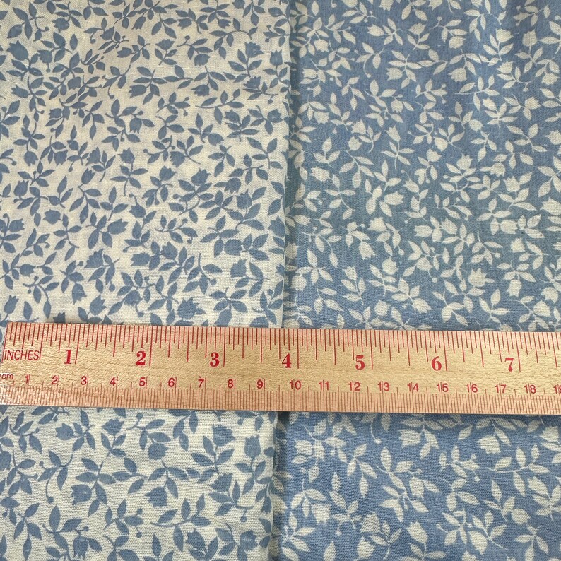 May include: Two fabric swatches with a white background and a blue floral pattern. A ruler is placed across the swatches, showing the measurement in inches.