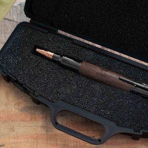 Black Walnut Bolt Action Pen resting inside of a Black Rifle Pen Case on top of a desk.