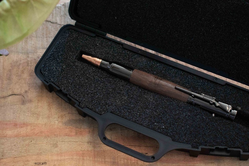 Black Walnut Bolt Action Pen resting inside of a Black Rifle Pen Case on top of a desk.