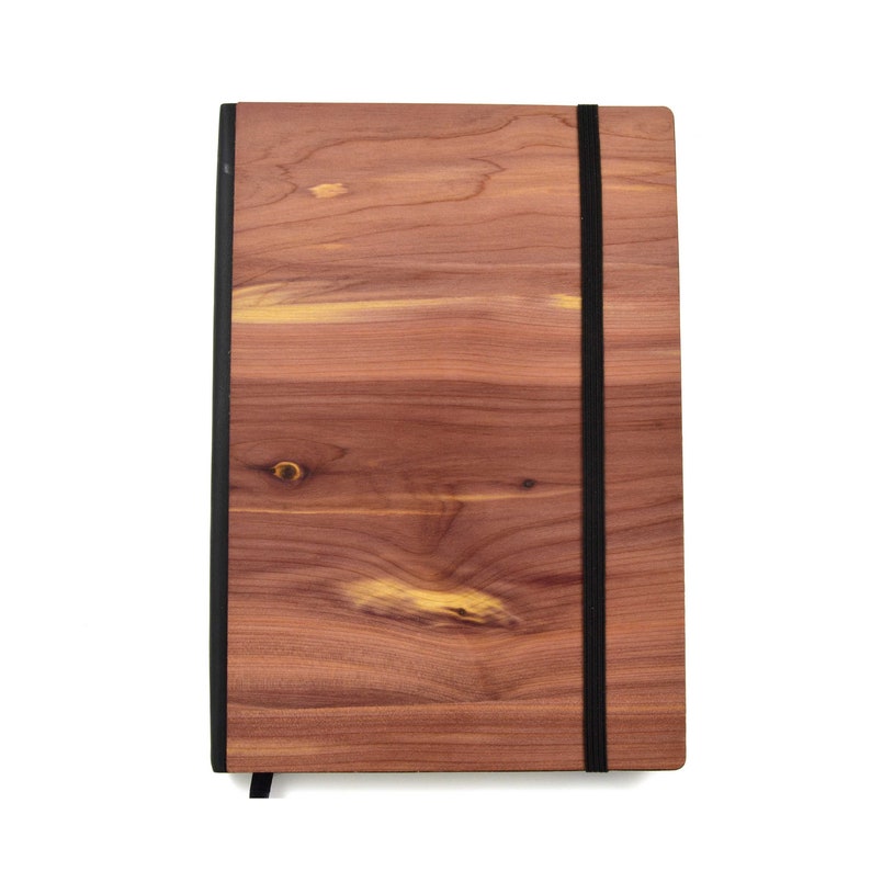 May include: A wooden journal with a black elastic closure. The cover is made of cedar wood with a natural wood grain pattern.
