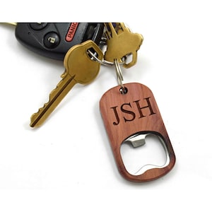 May include: A wooden bottle opener keychain with a metal opener and the initials JSH engraved on the front.