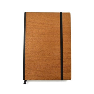 May include: A rectangular notebook featuring a light brown wood grain cover with a visible natural texture. The notebook is secured by a vertical black elastic band that wraps around the front cover, and a black fabric bookmark extends from the bottom.