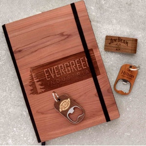 May include: A wooden journal with a black elastic closure and a laser-engraved logo that reads "EVERGREEN INDUSTRIES". The journal is accompanied by three wooden bottle openers with different logos: "Dickies", "Hilton Hotels", and "Jim Beam".