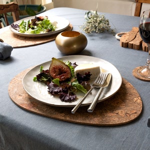 Pu&ograve; includere: Un piatto ovale bianco con un'insalata di misticanza, un fico tagliato a met&agrave; e un cubetto di formaggio bianco. Il piatto &egrave; su un sottopentola di sughero con un motivo marrone e bianco. Due forchette d'argento e un coltello d'argento sono sul piatto.