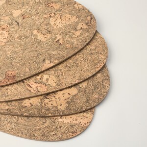 Pu&ograve; includere: Quattro sottobicchieri rotondi in sughero impilati. I sottobicchieri sono di colore marrone chiaro con un motivo screziato.