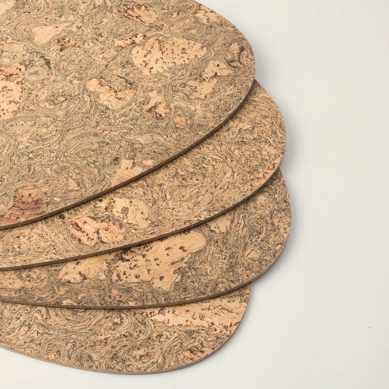 Pu&ograve; includere: Quattro sottobicchieri rotondi in sughero impilati. I sottobicchieri sono di colore marrone chiaro con un motivo screziato.