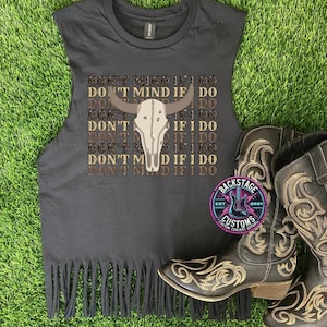 May include: Black sleeveless shirt with a fringe hem. The shirt features a brown and white cow skull graphic with the text "Don't Mind If I Do" repeated multiple times.
