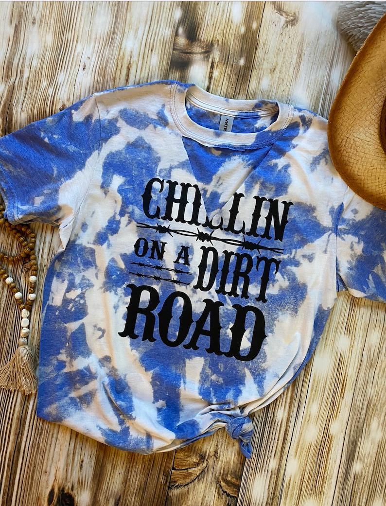 May include: A blue and white tie-dye t-shirt with the text "Chillin on a Dirt Road" in black lettering.