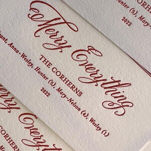 May include: Off-white textured paper cards featuring deep red ink. The text reads Merry Everything, THE CORHERNS, Anna-Wesley, Hunter (5), Mary-Nelson (4), Wesley (1), and 2022. The design uses a combination of elegant script and block lettering.
