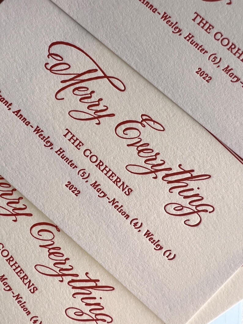 May include: Off-white textured paper cards featuring deep red ink. The text reads Merry Everything, THE CORHERNS, Anna-Wesley, Hunter (5), Mary-Nelson (4), Wesley (1), and 2022. The design uses a combination of elegant script and block lettering.