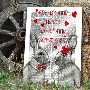 May include: A black and white illustration of two bunnies with red hearts and a red bow on one bunny. The text "Everybunny needs somebunny sometimes" is printed on a vintage book page background.