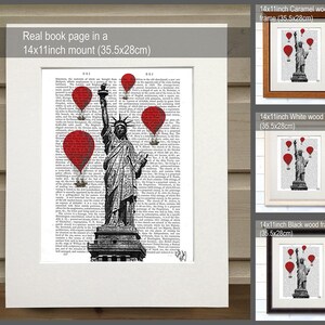 May include: A black and white illustration of the Statue of Liberty with red hot air balloons flying above her. The illustration is printed on a book page and framed in a white wood frame. The frame is 14 inches by 11 inches and measures 35.5 cm by 28 cm.