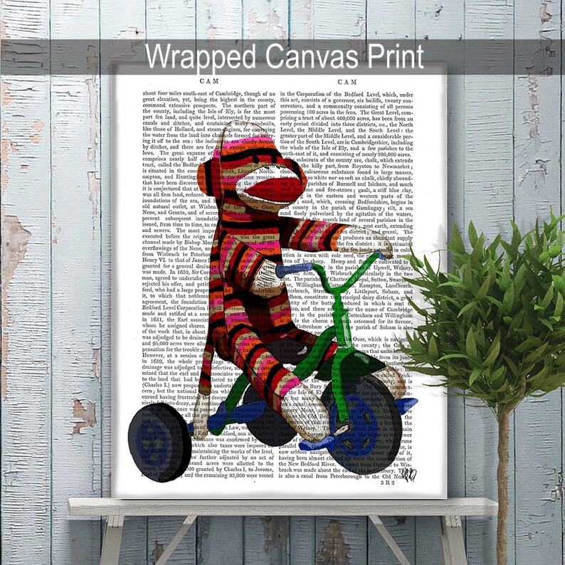 May include: A red and white striped monkey doll riding a green tricycle with blue wheels. The monkey is wearing a red and white striped hat and has a red nose. The tricycle has a basket on the front and a seat on the back. The background is a vintage book page with text.