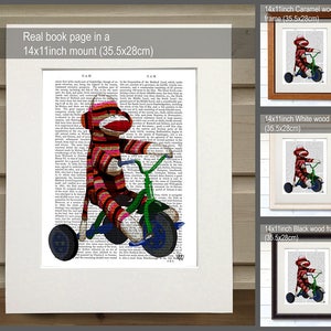 May include: A red and white striped sock monkey riding a green tricycle on a book page. The book page is framed in a 14x11 inch caramel wood frame. The image is also shown in white and black wood frames.