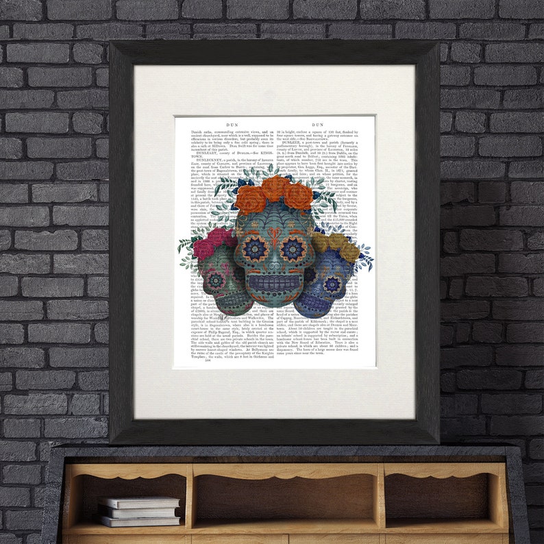 May include: Three colorful sugar skulls with floral headbands on a vintage book page background. The skulls are blue, green, and yellow with intricate designs and flowers.
