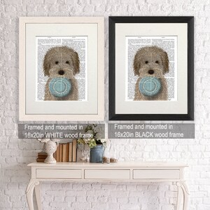 May include: Two framed prints of a brown and white dog holding a blue and white frisbee. The print on the left is framed in a white frame and the print on the right is framed in a black frame. Both frames are 16x20 inches.