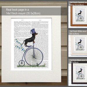 May include: A black and tan dachshund wearing a blue top hat rides a blue penny-farthing bicycle. The bicycle has a blue seat and blue streamers. The dachshund is on a page from an old book with text about the word "PAT." The image is framed in three different colors: caramel, white, and black.
