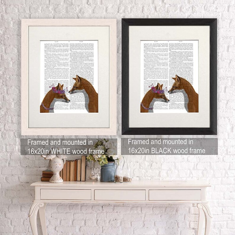 May include: Two foxes with floral crowns are looking at each other. The image is framed and mounted in a white wood frame. The text "Framed and mounted in 16x20in WHITE wood frame" is below the image.