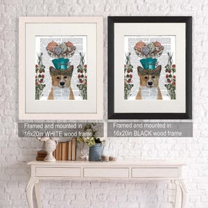 May include: A framed print of a corgi wearing a blue and white hat with hot air balloons on top. The print is surrounded by a white border and is framed in a white wood frame. The print is mounted on a white wall. The text "Framed and mounted in 16x20in WHITE wood frame" is below the print.