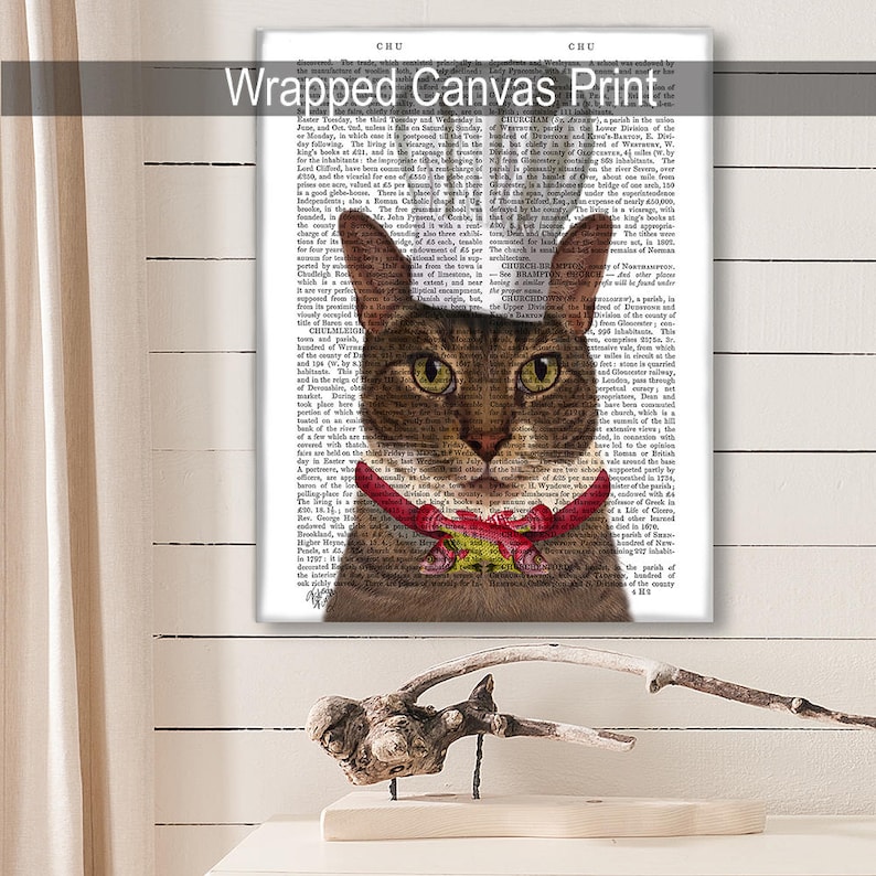 May include: A brown tabby cat with green eyes wearing a red bow tie with a gold bell. The cat is looking directly at the viewer. The background is a black and white page of text.