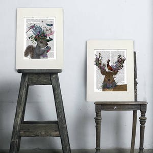 Puede incluir: Dos impresiones enmarcadas de ilustraciones de animales con acentos florales y de p&aacute;jaros. La primera impresi&oacute;n presenta una ardilla con un sombrero con flores y p&aacute;jaros. La segunda impresi&oacute;n presenta un ciervo con cuernos adornados con flores y un p&aacute;jaro.