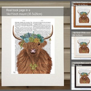 May include: A Highland cow with a floral crown on a book page background. The image is available in three frame options: caramel wood, white wood, and black wood. Each frame measures 14x11 inches (35.5x28 cm).