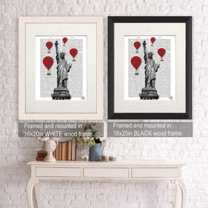 May include: A black and white illustration of the Statue of Liberty with red hot air balloons in the background. The image is framed in a white wood frame and a black wood frame. The text "Framed and mounted in 16x20in WHITE wood frame" and "Framed and mounted in 16x20in BLACK wood frame" is below each image.