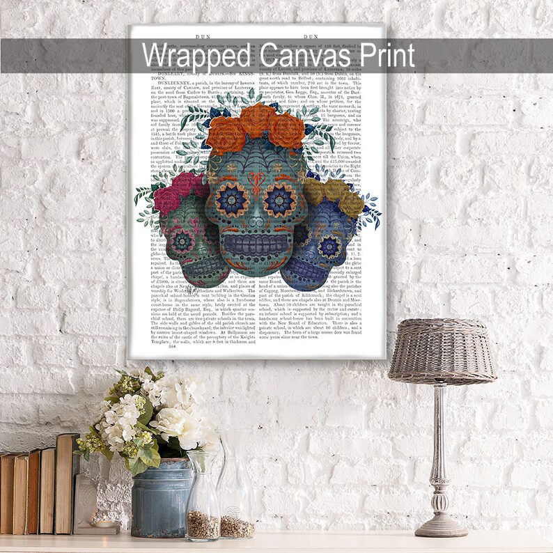 May include: Three colorful sugar skulls with floral accents on a vintage book page background. The skulls are blue, green, and teal with intricate details and floral crowns. The background is a black and white page of text.