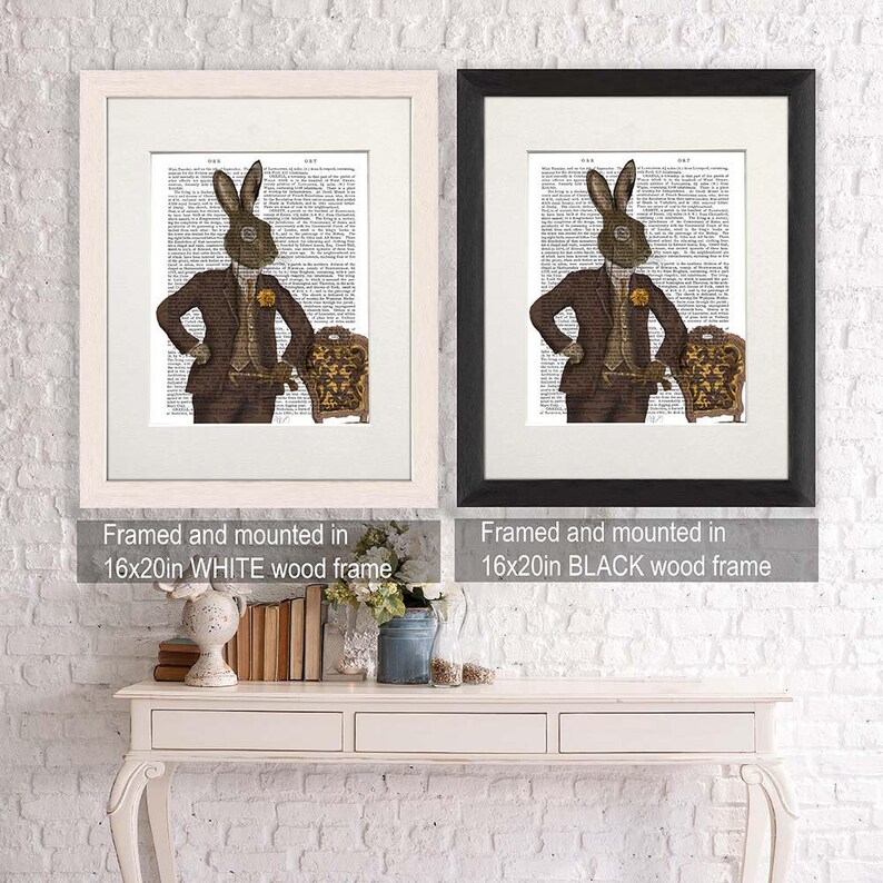 May include: Two framed prints of a brown rabbit wearing a suit and a monocle, standing next to a chair. The print on the left is framed in white, and the print on the right is framed in black. Both frames are 16 inches by 20 inches.